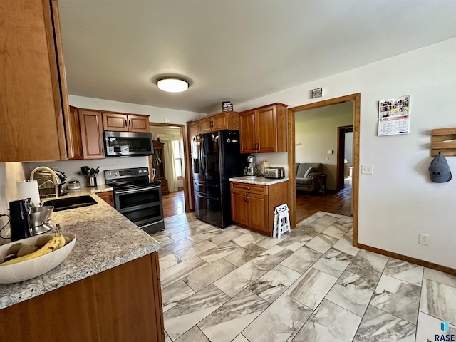 kitchen featuring appliances with stainless steel finishes, brown cabinets, a sink, baseboards, and marble finish floor