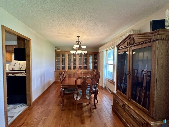 dining space featuring a textured ceiling, a notable chandelier, and wood finished floors