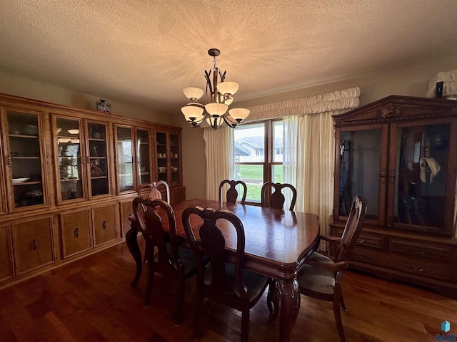 dining space featuring a textured ceiling, a notable chandelier, and dark wood-style floors