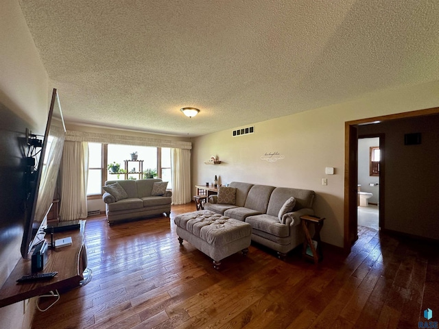 living area featuring dark wood-style flooring, a textured ceiling, and visible vents