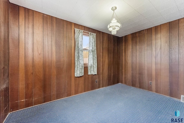 carpeted spare room featuring wood walls