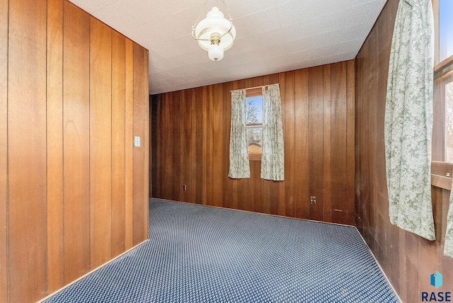 carpeted spare room with wooden walls