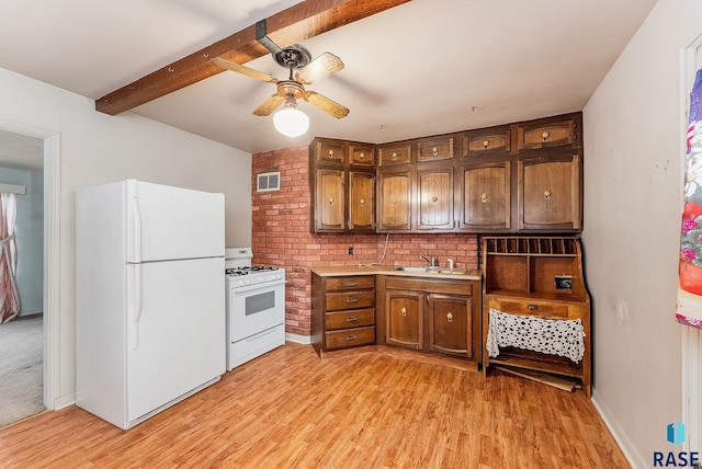kitchen with visible vents, a sink, light countertops, light wood finished floors, and white appliances