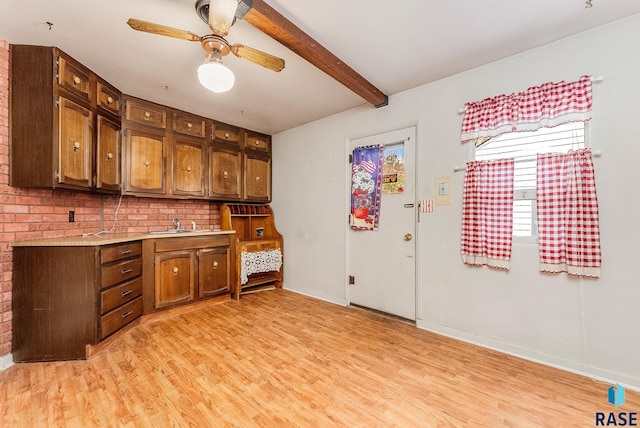 kitchen featuring light countertops, ceiling fan, beam ceiling, and light wood-style floors