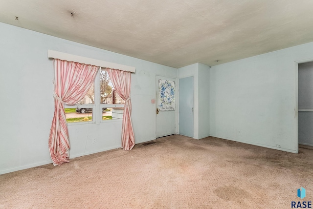 spare room featuring baseboards, carpet flooring, and visible vents