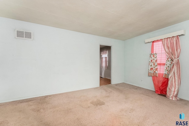 spare room with carpet floors, baseboards, and visible vents