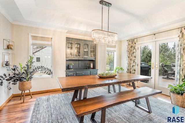dining room featuring an inviting chandelier, light wood-style floors, french doors, baseboards, and a tray ceiling