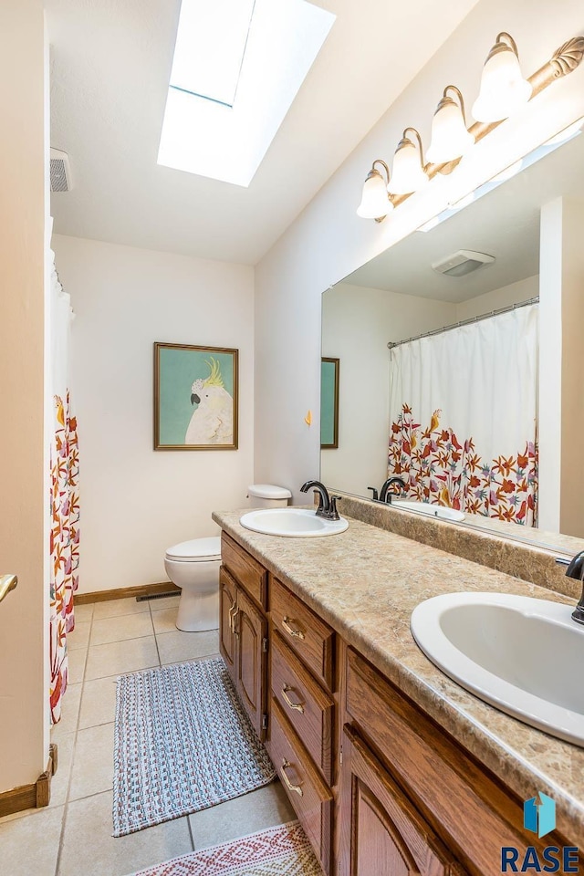 bathroom featuring a sink, tile patterned floors, toilet, and a skylight