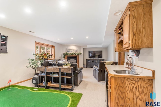 kitchen featuring a sink, light countertops, a glass covered fireplace, baseboards, and visible vents
