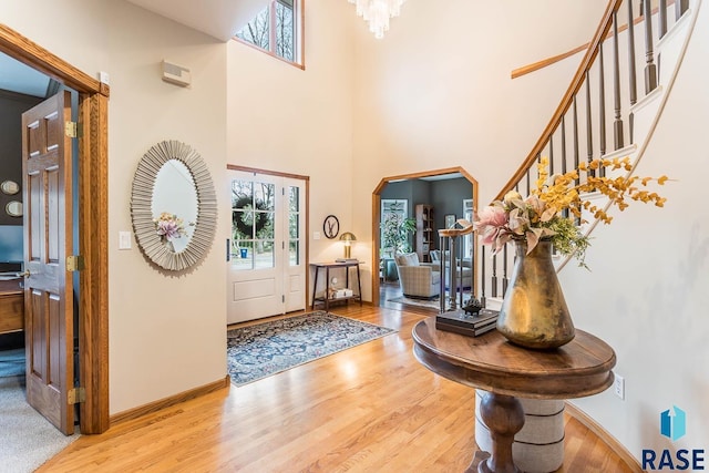 foyer with a towering ceiling, arched walkways, wood finished floors, stairway, and baseboards