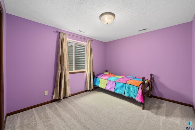 carpeted bedroom with visible vents, a textured ceiling, and baseboards