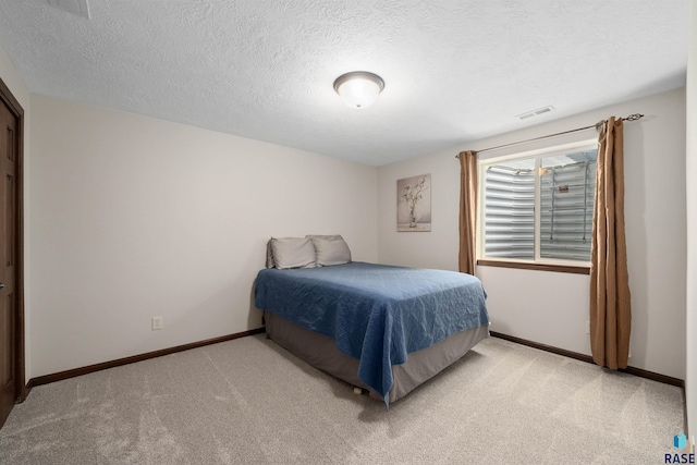 bedroom with visible vents, a textured ceiling, and light colored carpet