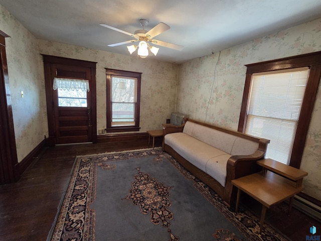 living area with baseboards, a ceiling fan, wallpapered walls, and wood finished floors