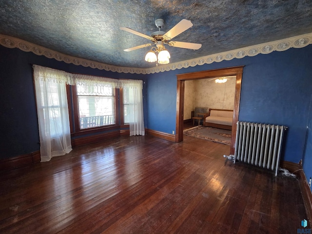 empty room featuring radiator, baseboards, and hardwood / wood-style flooring