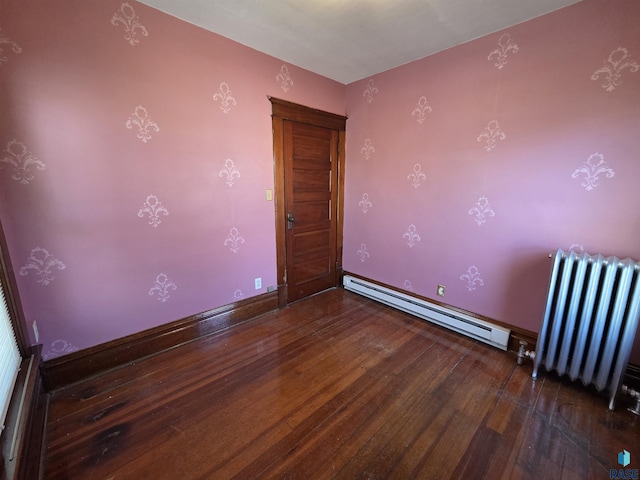 spare room featuring baseboard heating, radiator, and wood finished floors