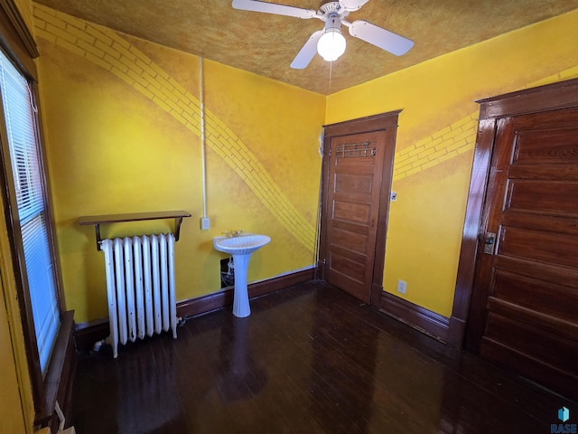 spare room featuring baseboards, ceiling fan, radiator heating unit, and hardwood / wood-style floors