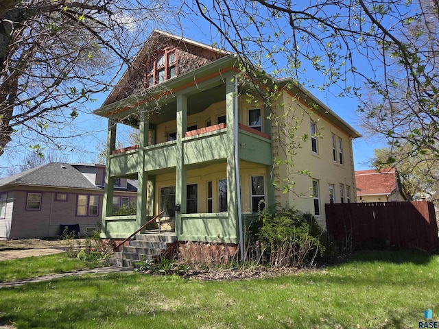 back of house featuring a lawn, fence, a balcony, and a porch