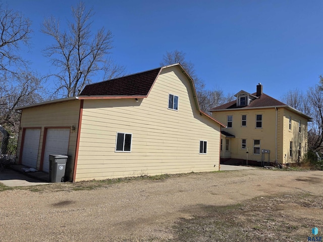 view of property exterior featuring a chimney and a garage