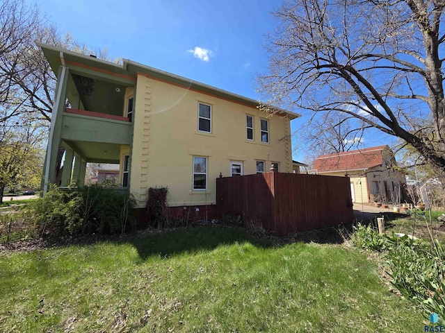 view of property exterior featuring fence, a balcony, and stucco siding