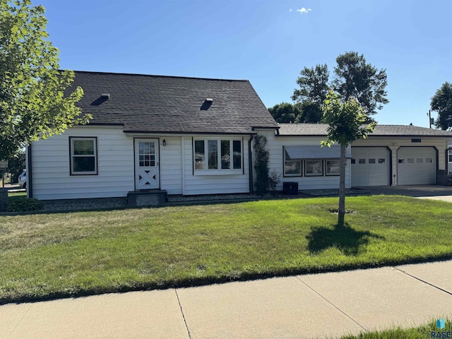 cape cod house featuring a garage, driveway, roof with shingles, and a front yard