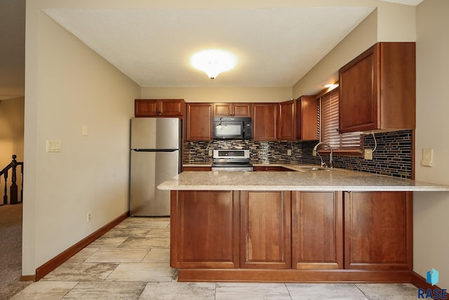 kitchen featuring stainless steel appliances, a peninsula, baseboards, a sink, and light countertops