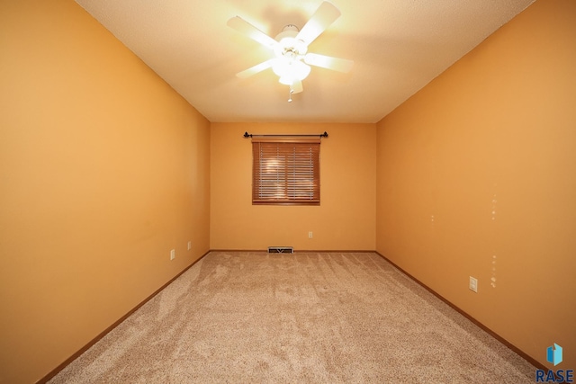 spare room featuring ceiling fan, light colored carpet, and baseboards