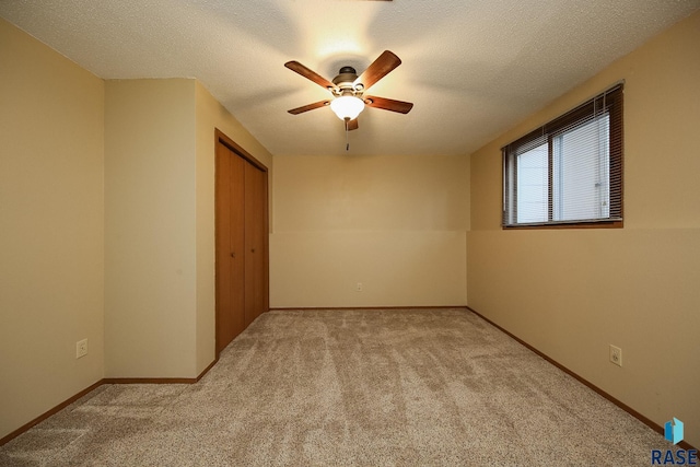 unfurnished bedroom featuring a ceiling fan, a closet, a textured ceiling, carpet, and baseboards