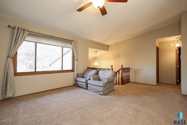 living area with an upstairs landing, ceiling fan, carpet, and vaulted ceiling