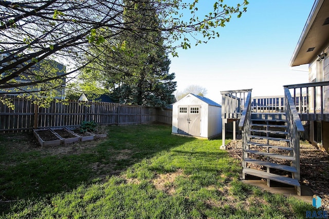view of yard with an outdoor structure, a storage unit, a fenced backyard, a wooden deck, and a garden