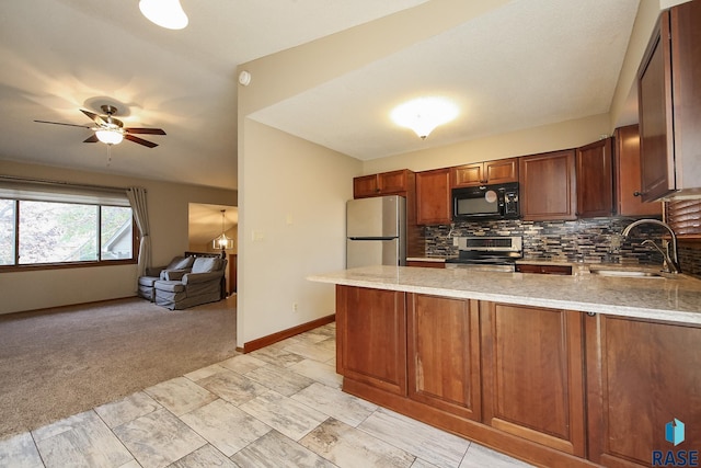 kitchen featuring a peninsula, a sink, light stone countertops, appliances with stainless steel finishes, and tasteful backsplash