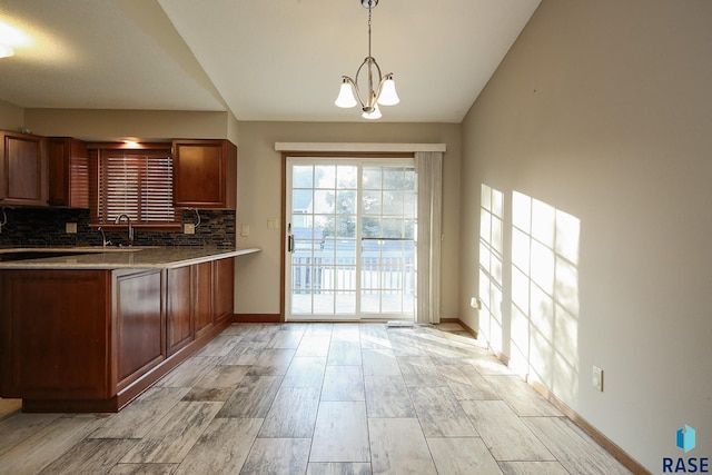 kitchen featuring tasteful backsplash, a sink, a chandelier, baseboards, and light wood-style flooring