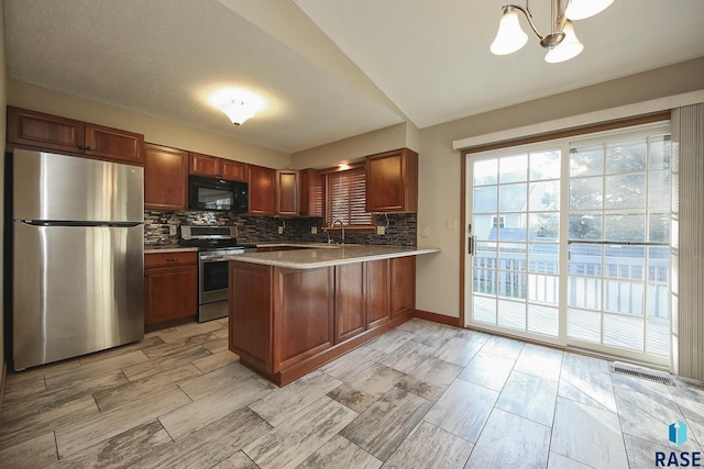 kitchen with a peninsula, tasteful backsplash, light countertops, wood tiled floor, and appliances with stainless steel finishes