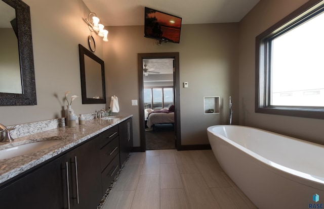 bathroom with ensuite bath, a freestanding tub, a sink, and double vanity
