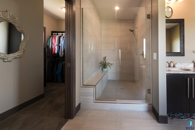 full bathroom with a shower stall, a spacious closet, and baseboards
