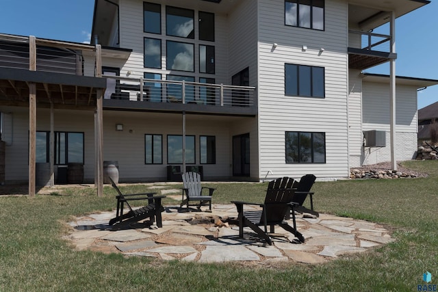 rear view of house featuring a balcony, a yard, a patio area, and central AC
