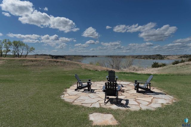view of home's community featuring an outdoor fire pit, a yard, a water view, and a patio