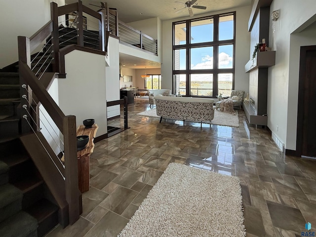 interior space with stairs, a wealth of natural light, baseboards, and a towering ceiling