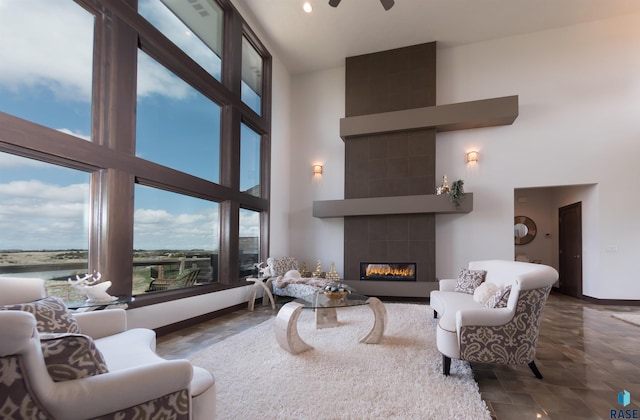 living area with a wealth of natural light, baseboards, a fireplace, and a towering ceiling