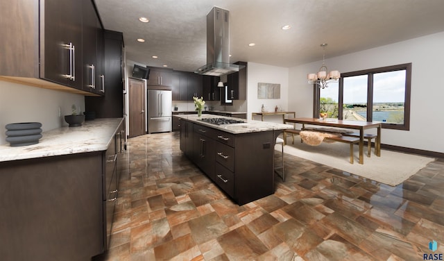 kitchen featuring appliances with stainless steel finishes, a center island, island exhaust hood, and stone finish flooring