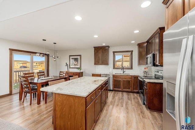 kitchen featuring a center island, plenty of natural light, a sink, light wood-style floors, and stainless steel appliances