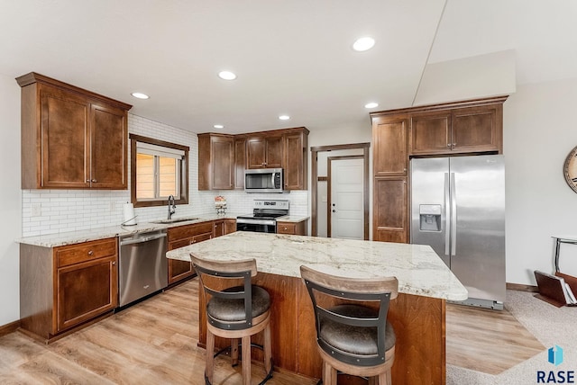 kitchen featuring stainless steel appliances, a sink, and light stone countertops