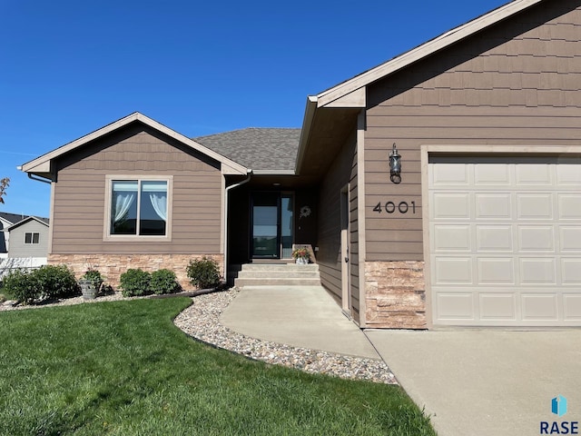 doorway to property with a yard, stone siding, and an attached garage