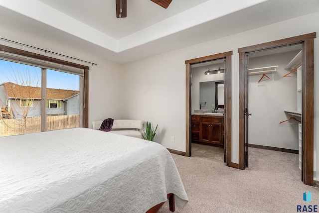 bedroom with connected bathroom, a sink, baseboards, ceiling fan, and light carpet