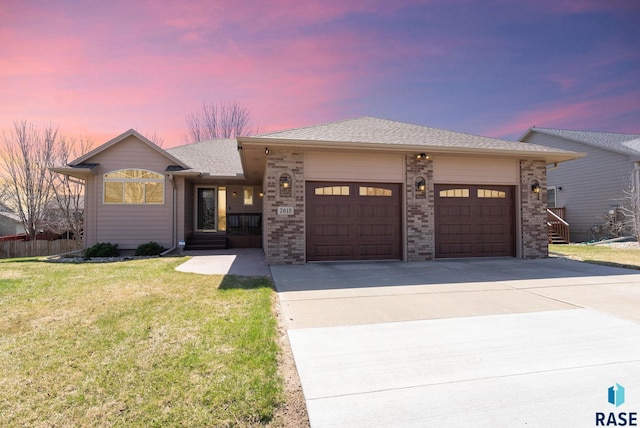 view of front of house with a garage, a yard, concrete driveway, brick siding, and roof with shingles