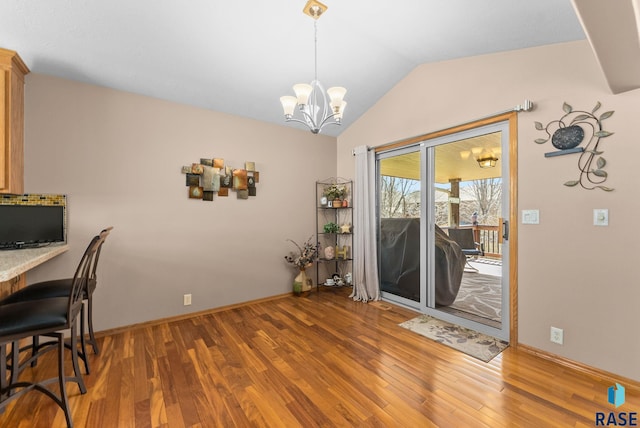 dining room featuring baseboards, a notable chandelier, lofted ceiling, and wood finished floors