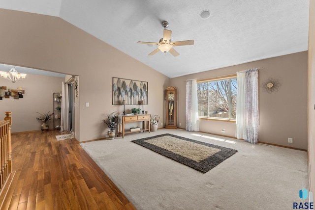 living area with baseboards, wood finished floors, ceiling fan with notable chandelier, and high vaulted ceiling