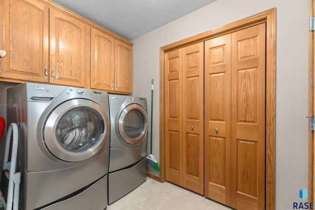 clothes washing area featuring washing machine and dryer, cabinet space, and light tile patterned floors