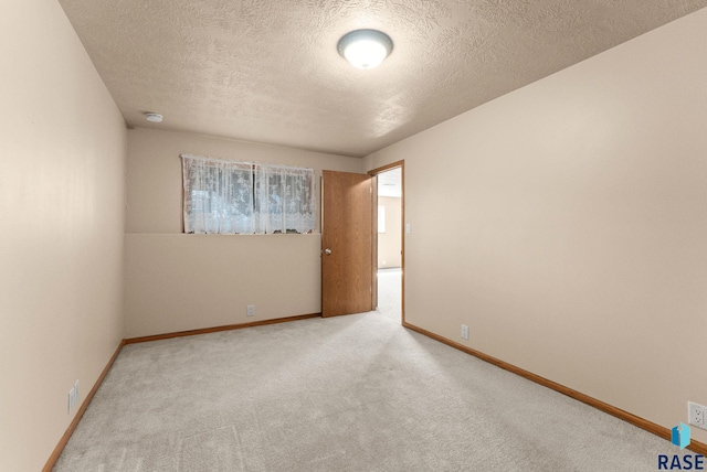 carpeted empty room featuring baseboards and a textured ceiling