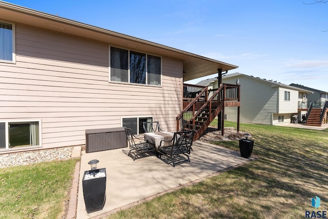 back of property with stairway, a deck, a patio area, and a lawn