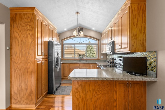 kitchen featuring a sink, black microwave, stainless steel fridge with ice dispenser, a peninsula, and electric stove